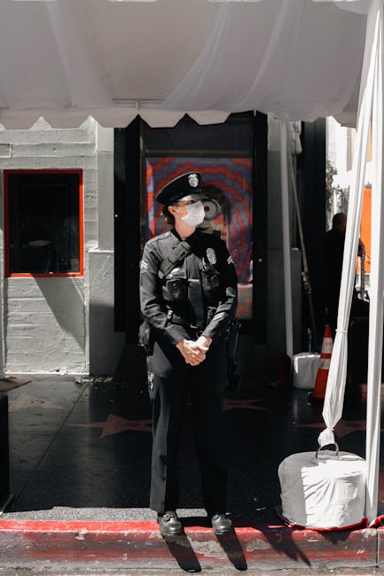 Female police officer standing outdoors with face mask during daylight.