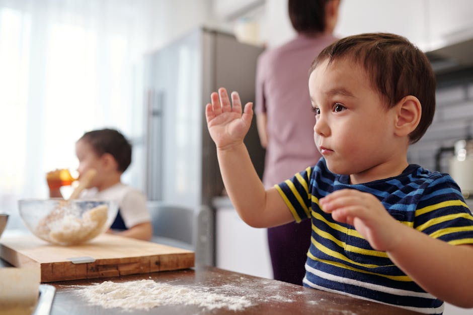 Two young children baking in a home kitchen, learning and having fun.