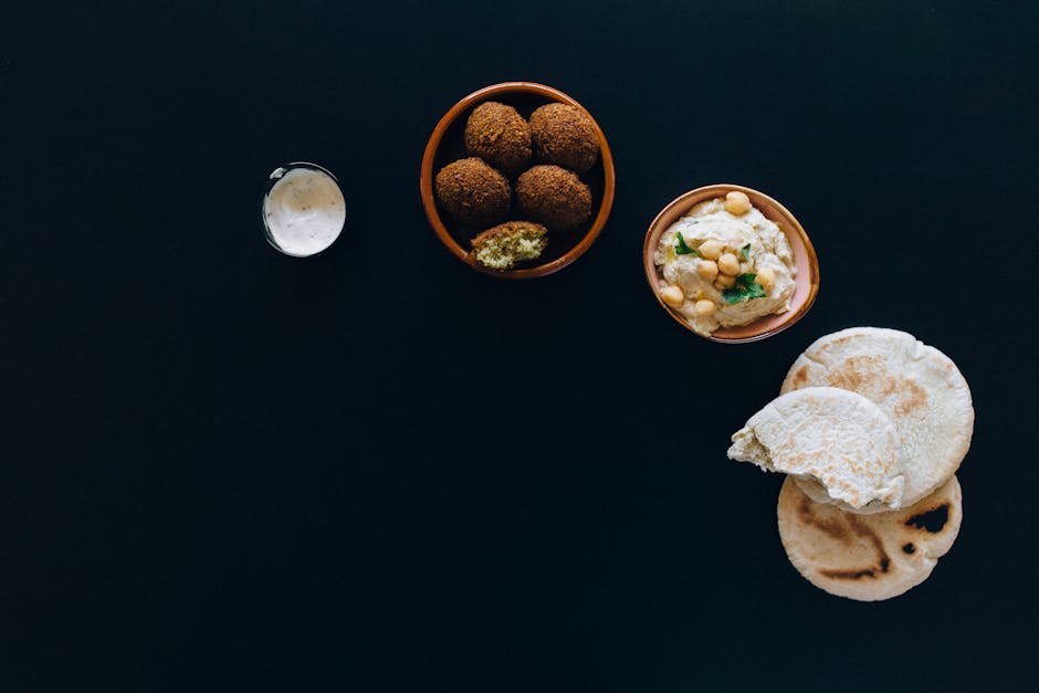 A delicious spread of falafel, hummus, and pita bread on dark background.
