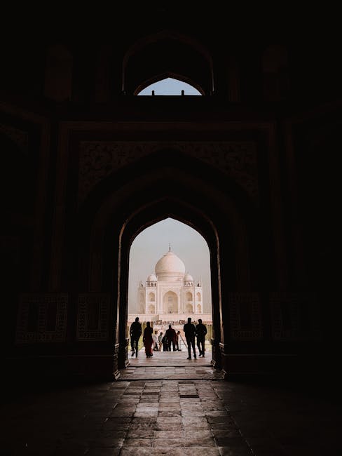 A striking silhouette of people entering the iconic Taj Mahal through a grand arched entrance.