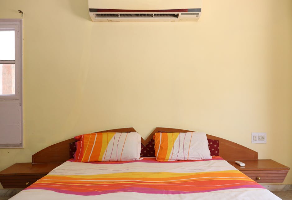 Brightly colored bedroom in Ahmedabad featuring a comfortable bed and air conditioning unit.