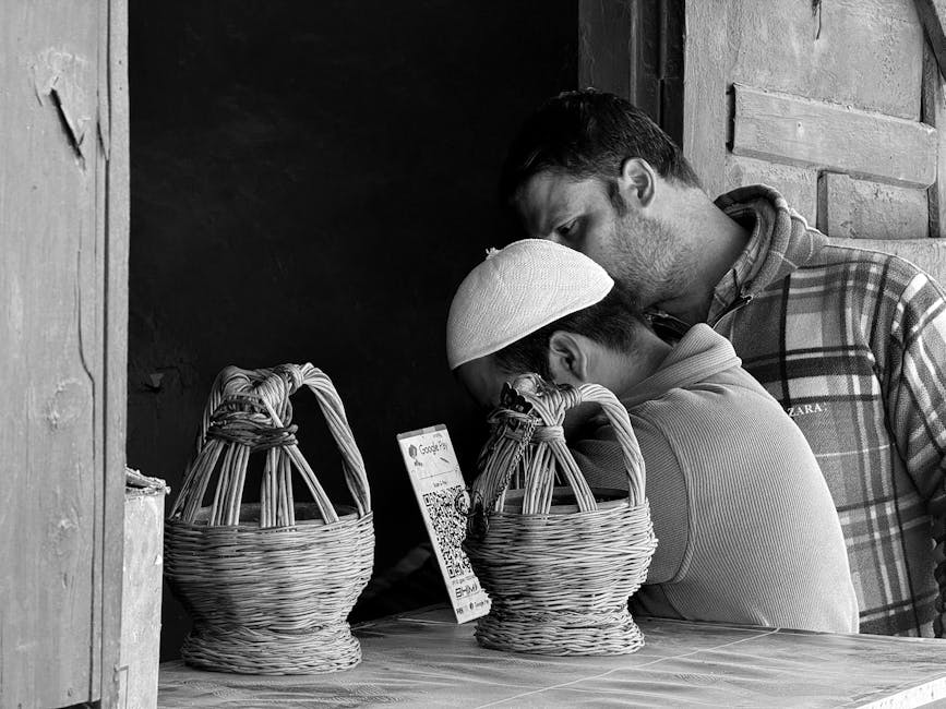 Black and white image of two men at a market stall in Kishtwar, India, engaging with a QR code.