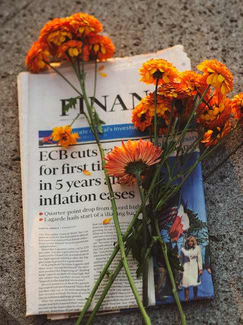 Marigold flowers on financial newspaper symbolize economic reflection. Warm afternoon light.