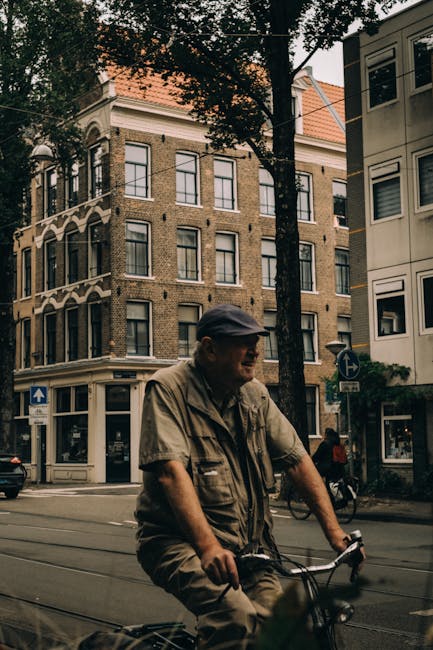 Man cycling through historic Amsterdam with classic architecture in view.
