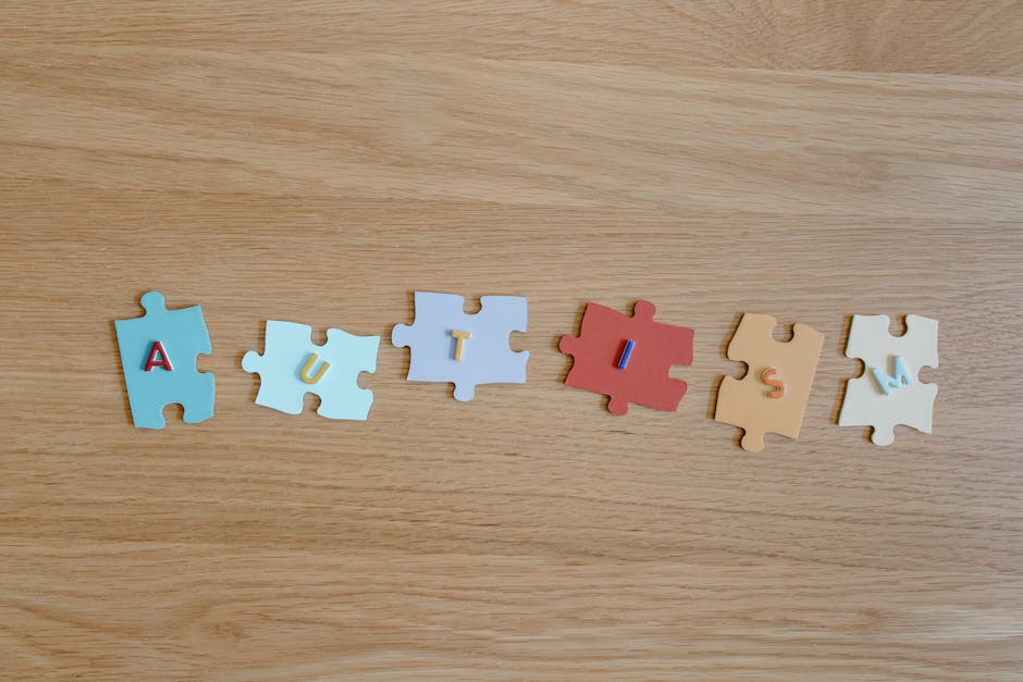 Colorful puzzle pieces spelling 'autism' on a wooden surface, promoting autism awareness.