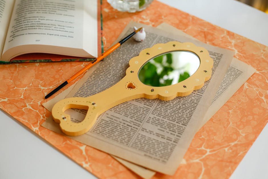 Elegant desk arrangement featuring a mirror, open book, and writing tools for an artistic flair.