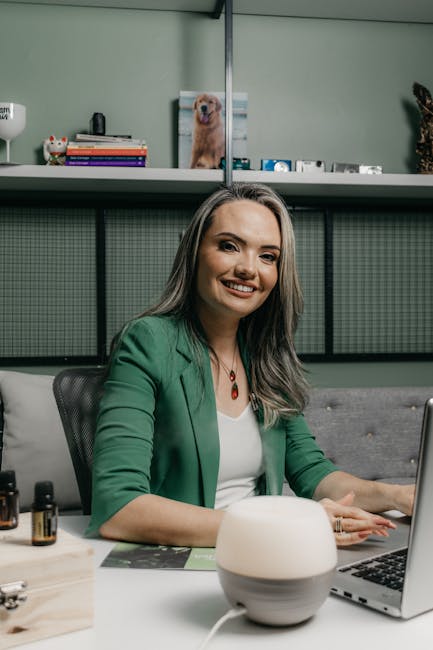 Businesswoman in green suit working at desk with laptop and aroma diffuser.