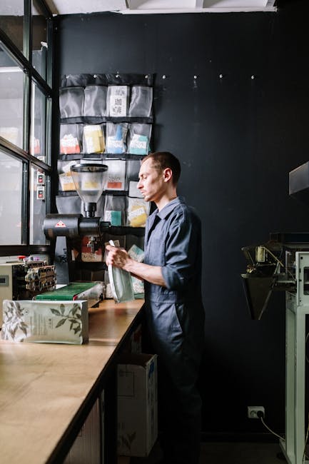 A man in uniform works on coffee packaging in a modern coffee roasting workshop.