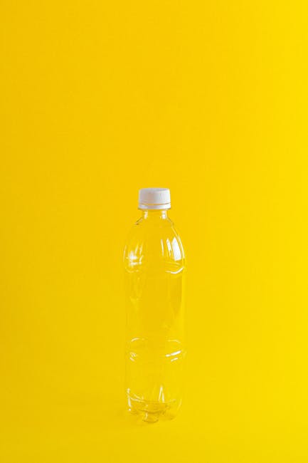 Conceptual image of a translucent plastic bottle highlighting environmental issues on a vivid yellow background.