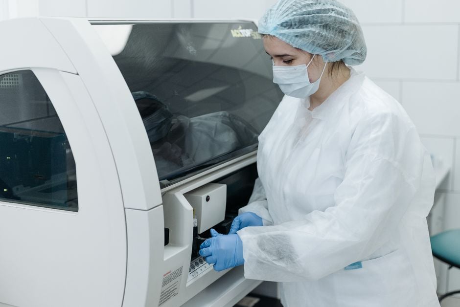 A scientist in protective gear working with advanced laboratory equipment for research purposes.