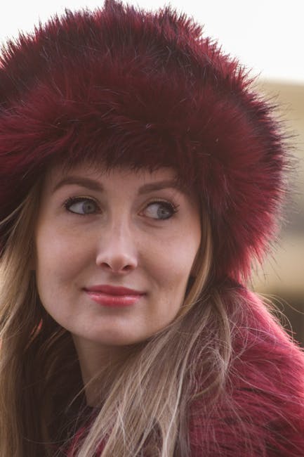 Stylish woman wearing a red fur hat, captured in a candid outdoor portrait.