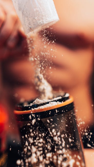 Dynamic shot of protein powder being added to a shaker, fitness concept.