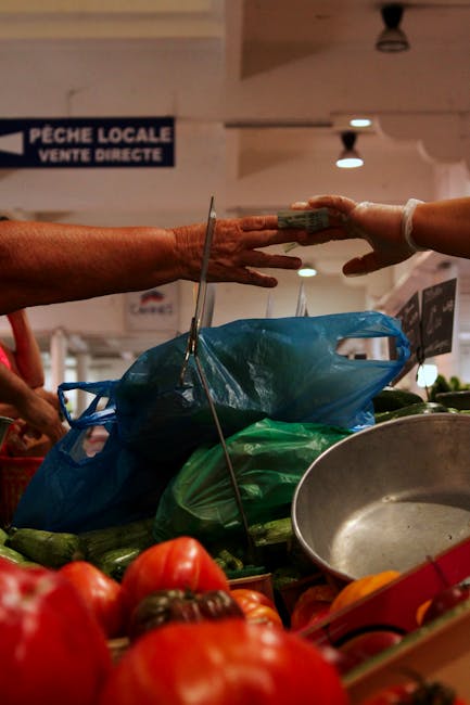 Hands exchanging cash at a local market vendor, with fresh vegetables in focus.