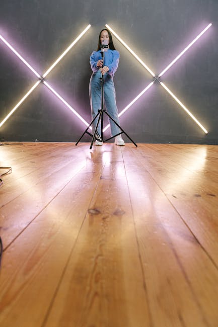 A young woman adjusts a tripod in a stylish studio with neon light decorations.