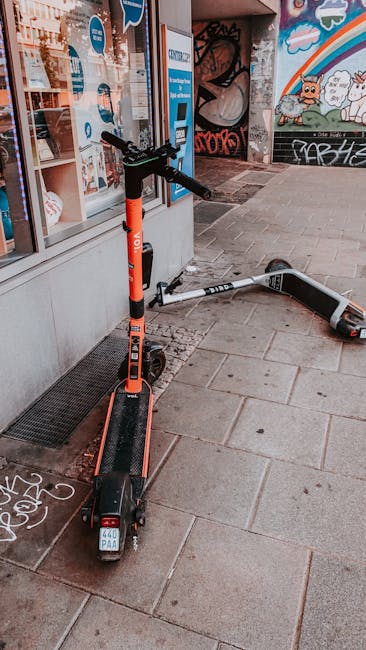 Two electric scooters parked on a graffiti-decorated street corner, showcasing urban lifestyle.
