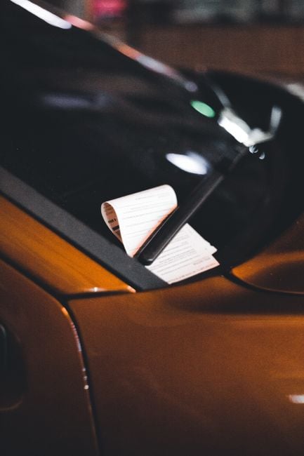Close-up of a parking ticket on a car windshield at night, highlighting urban parking issues.