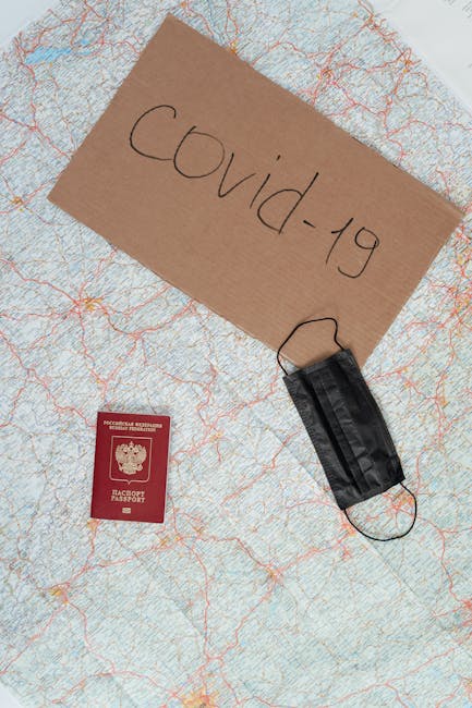 Flat lay of travel essentials during Covid-19 pandemic: map, black mask, and passport.