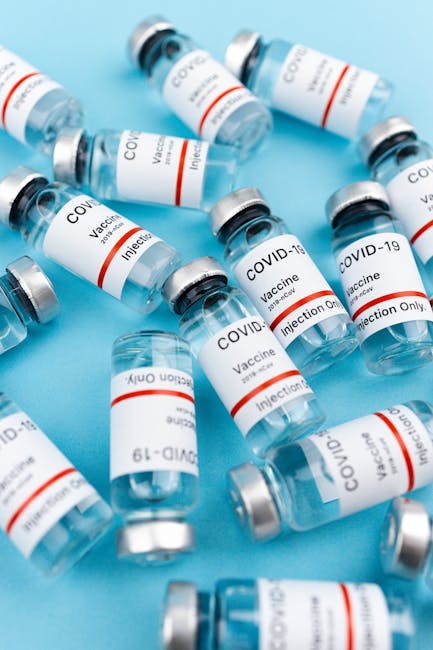 Multiple COVID-19 vaccine vials on a blue background, symbolizing vaccination efforts.