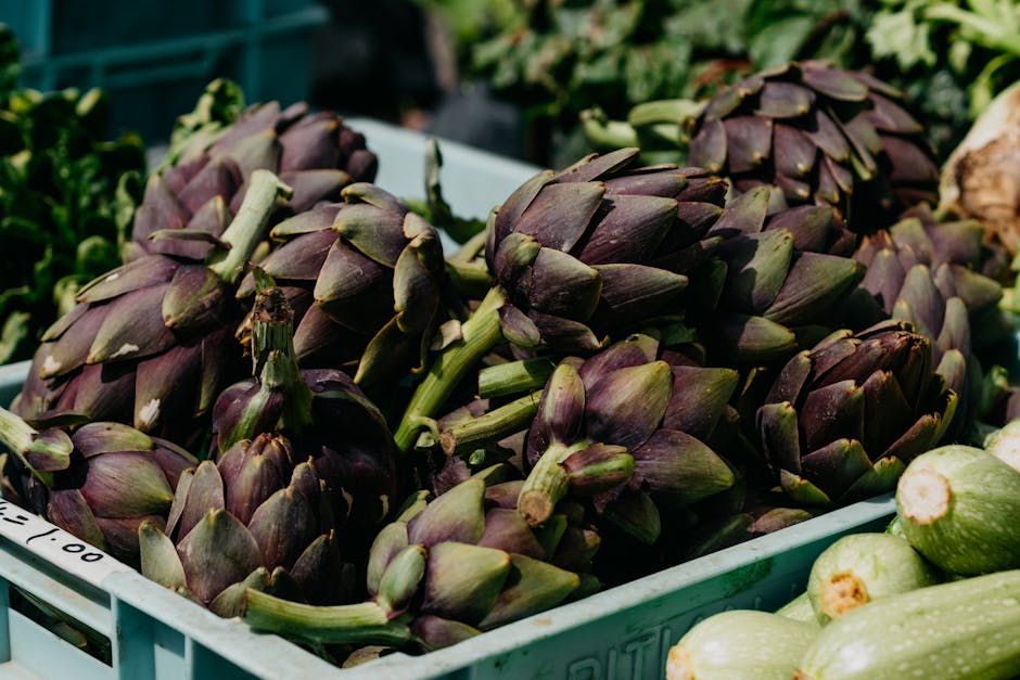 Close-up of fresh artichokes in a blue tray at an outdoor market.