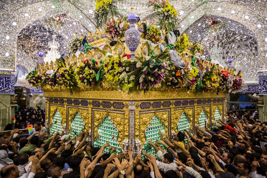 Crowded scene of devotees reaching for a beautifully adorned Islamic shrine under shimmering lights.