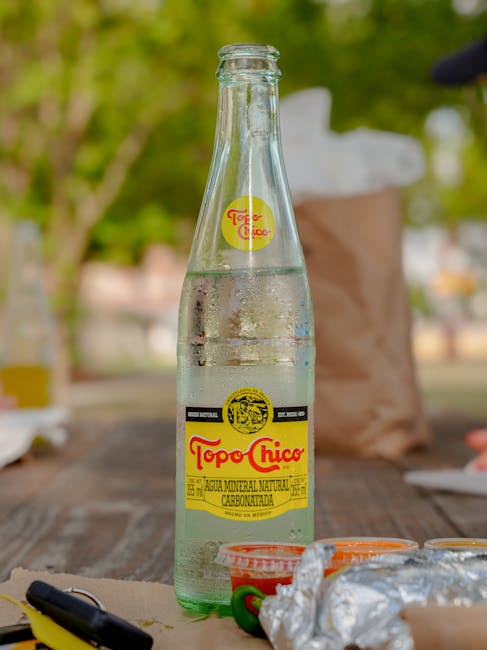 Refreshing Topo Chico bottle on a picnic table in Houston park setting.