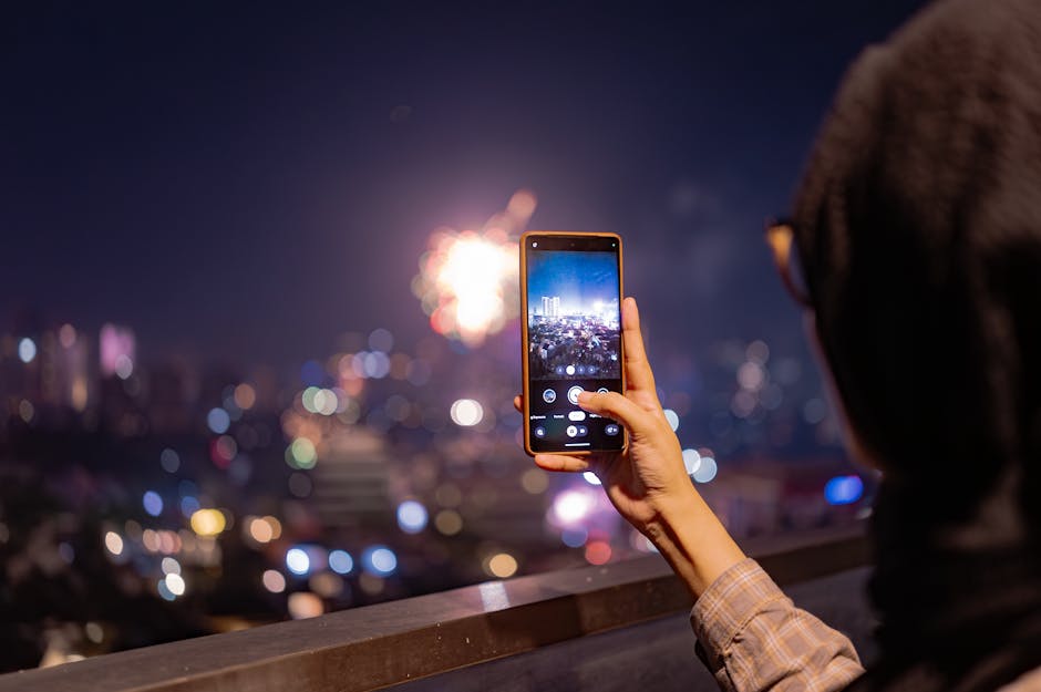 A person photographing vibrant fireworks in Jakarta at night with a smartphone. Urban cityscape in the background.