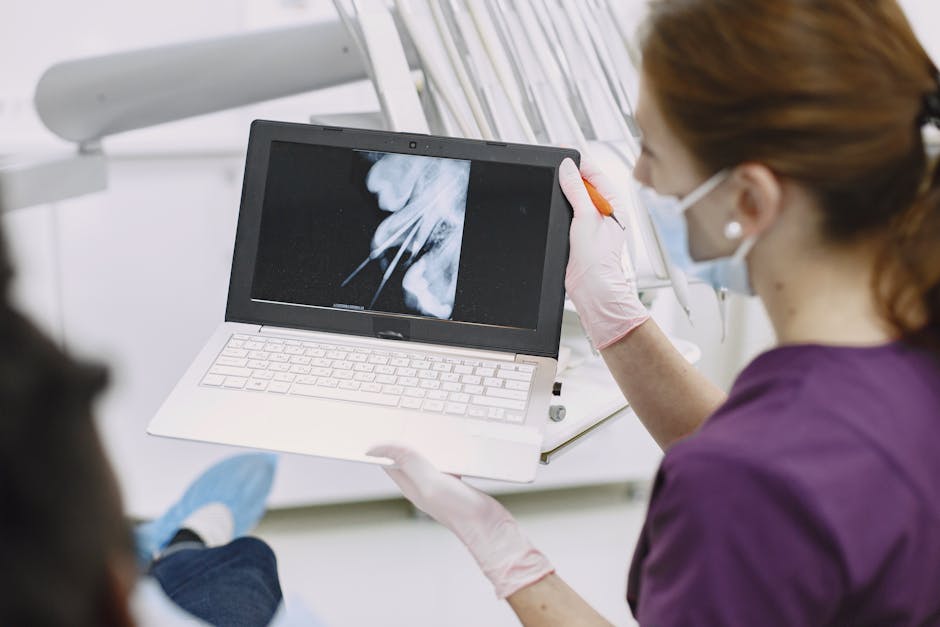 Dentist shows x-ray results on laptop to patient in dental clinic setting.