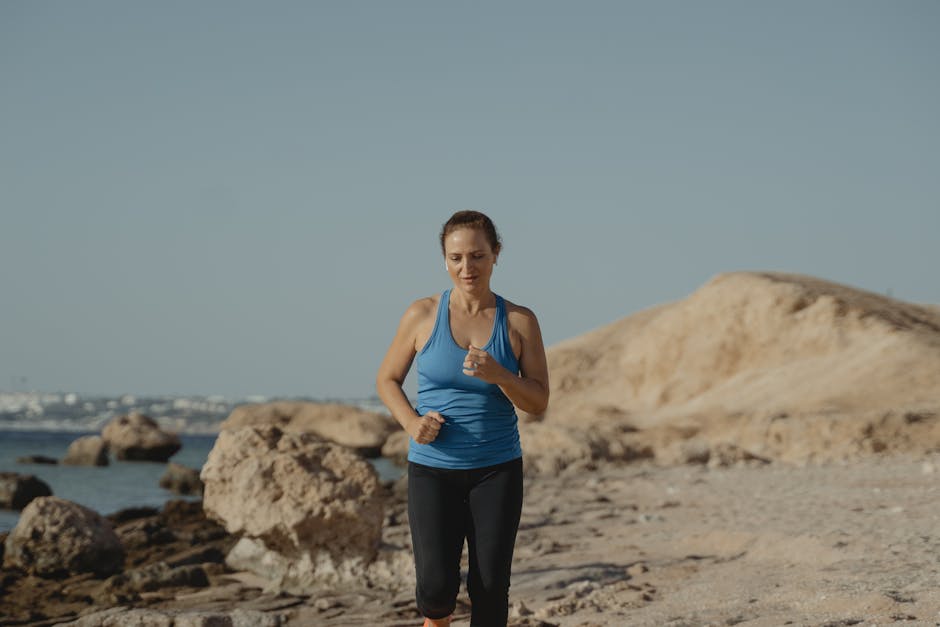 Woman jogging on a rocky beach path, promoting fitness and healthy lifestyle.