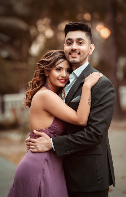 A couple elegantly posing outdoors in formal attire, exuding love and happiness.