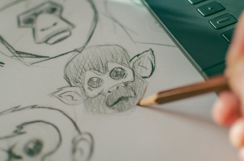 Close-up of hand sketching monkey faces on paper, showcasing artistic creativity.