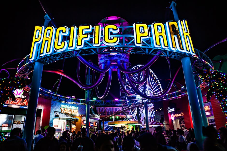 Colorful and lively night at Pacific Park with neon lights and a bustling crowd.