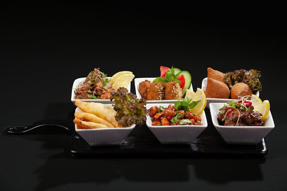 An appetizing selection of Mediterranean meze dishes served in small bowls on a black platter.