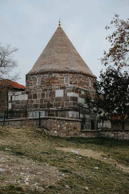 Medieval stone tower with conical roof in rural landscape, historical architecture.