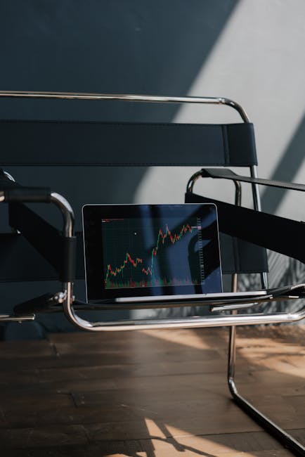 An empty designer chair with a tablet showing a stock market graph, creating a modern business atmosphere.