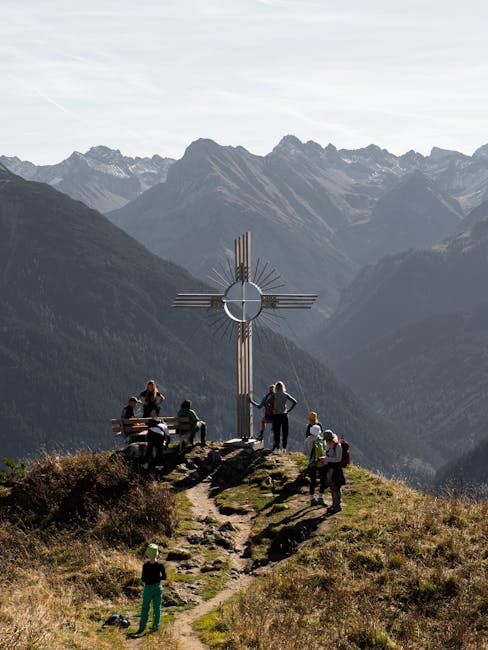 Group of hikers enjoying scenic views at a summit cross in the Austrian Alps.