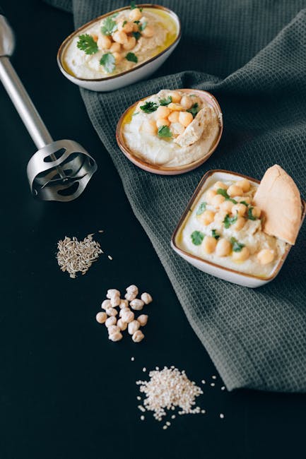 Top view of homemade hummus bowls with herbs and spices, perfect for Mediterranean cuisine lovers.