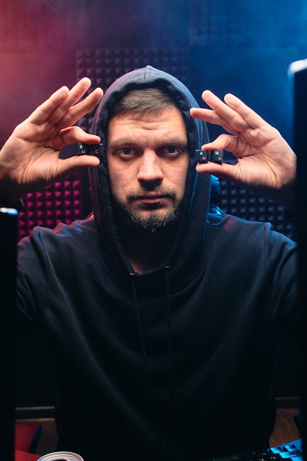 Portrait of a man in a hoodie with a serious expression holding computer keys in a tech-themed studio.