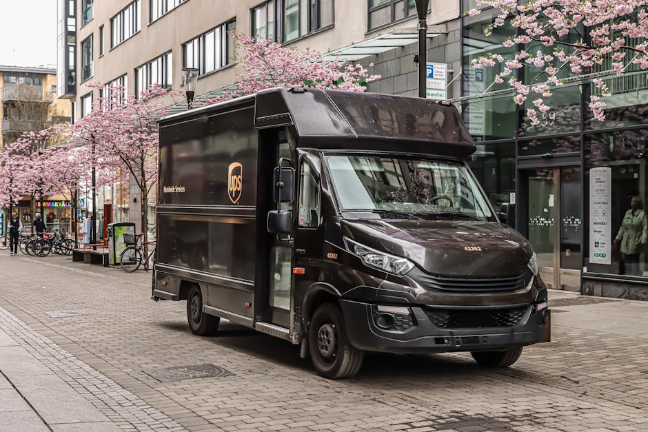 Black UPS delivery truck parked on a street in Jönköping, Sweden with cherry blossoms in spring.