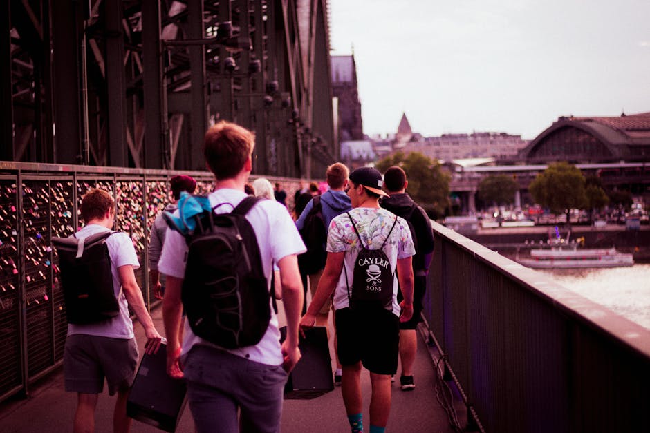 A group of men with backpacks walking on the Hohenzollern Bridge in Cologne during day.