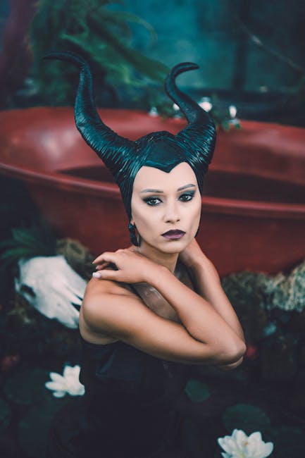 A woman in a dark, horned costume posing in a moody setting.