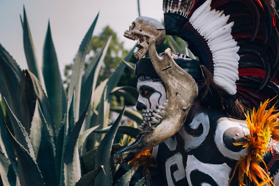 A vividly dressed man in Day of the Dead costume with skull headdress, outdoors in Mexico.