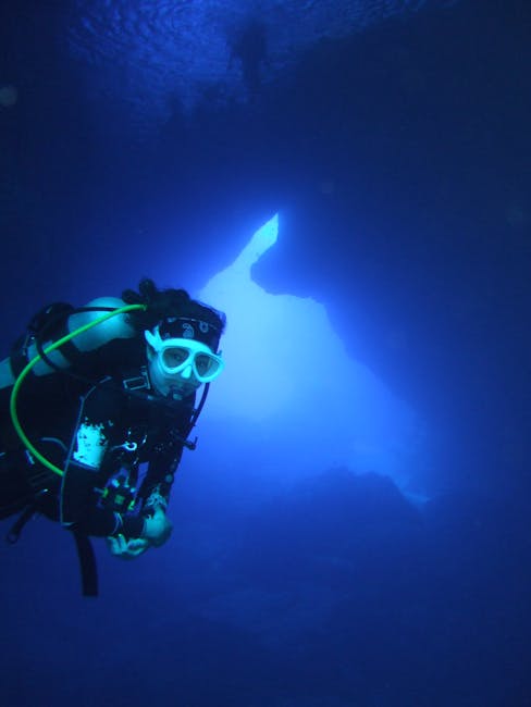 A scuba diver explores a vibrant blue underwater cave, creating a sense of adventure.