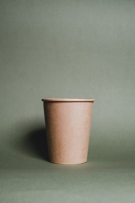 Eco-friendly paper cup on a green background symbolizing sustainability and minimalism.