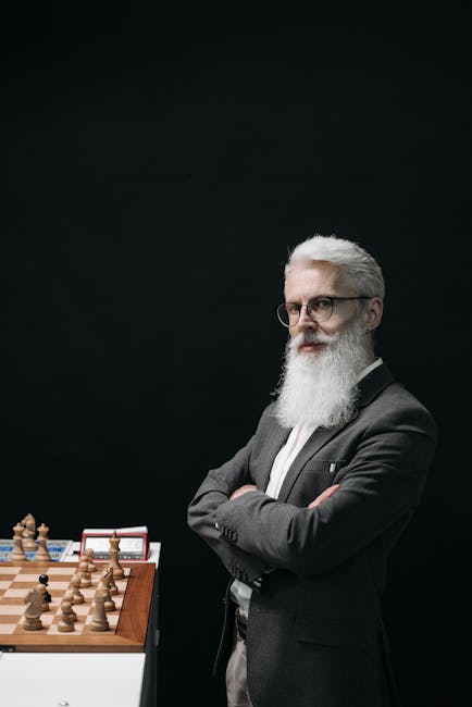 A bearded elderly man deeply focused on a chess game.