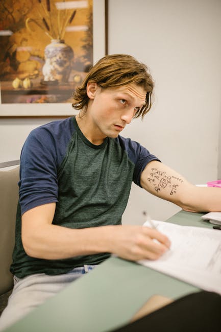Male college student appears to be cheating during an exam using notes written on his arm.