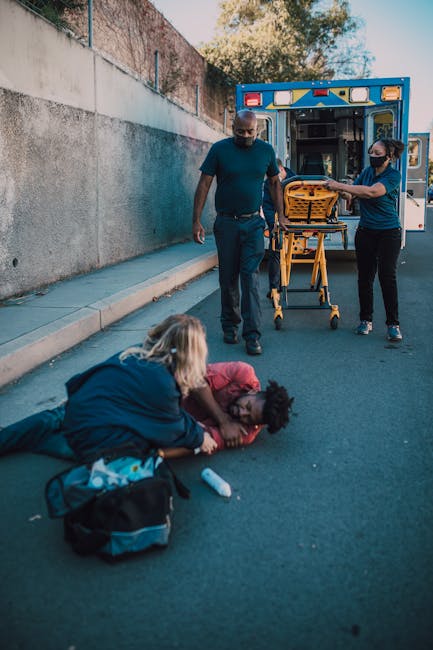 Paramedics assist an injured person on a roadside, showcasing emergency healthcare in action.
