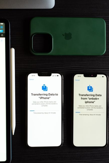 Two smartphones transferring data, showcasing modern mobile technology on a dark desk.