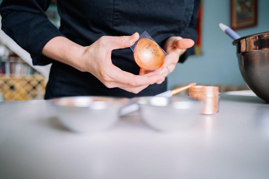 Close-up of a chef's hands preparing food in a modern kitchen setting with a copper bowl.