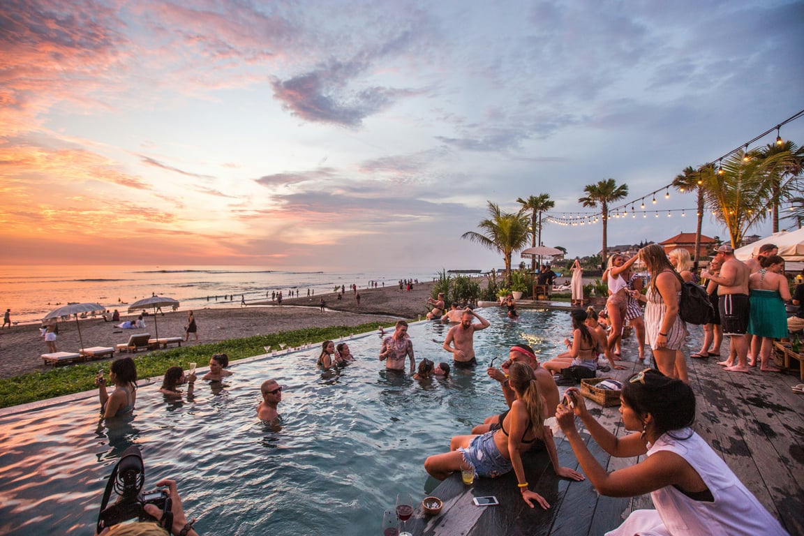 outdoor infinity pool at beach with string lights and sunset views