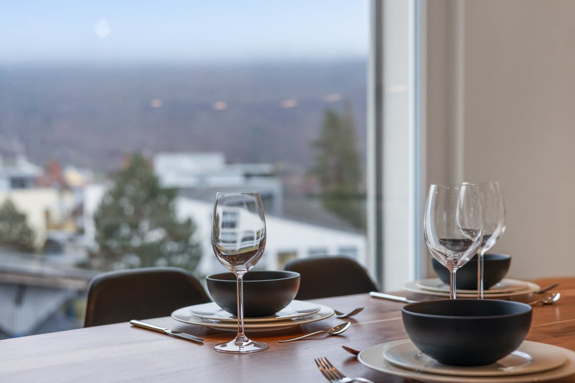 dining table with dark bowls and wine glasses overlooking hillside town view
